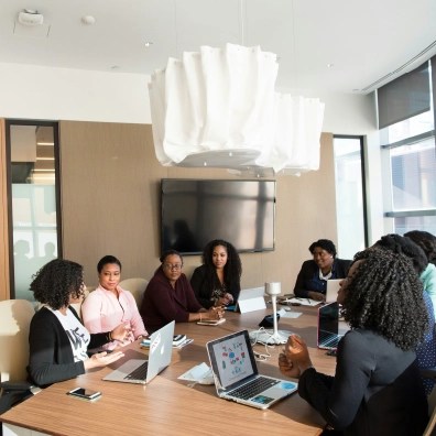 A group of employees sitting at a conference table with laptops in front of them in an office
