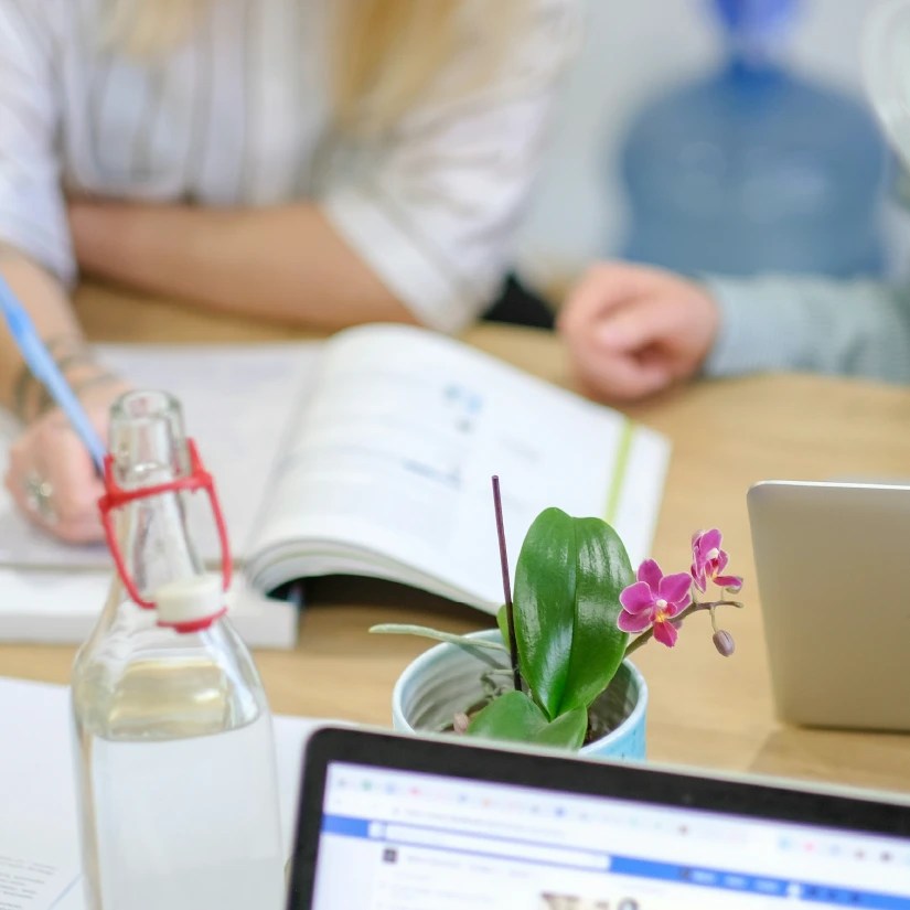 Someone sitting at a desk writing down notes in a notebook