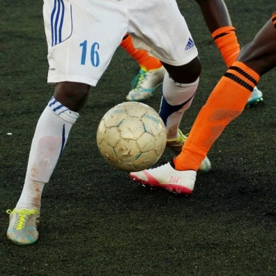 Two people playing soccer and fighting over the ball, only showing their legs