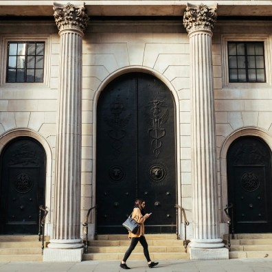 Someone walking in front of two pillars of a large building