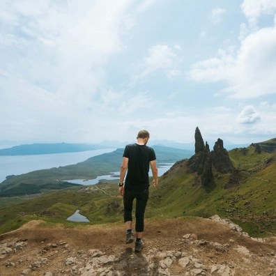 A male hiking in nature with with a path of a river and the ocean.