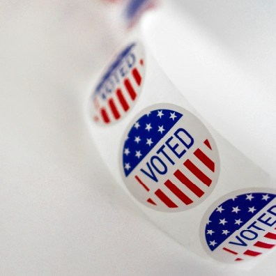 A roll of stickers that say "I VOTED" with the USA flag in the background