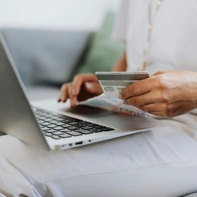 Someone typing their credit card information into a laptap.