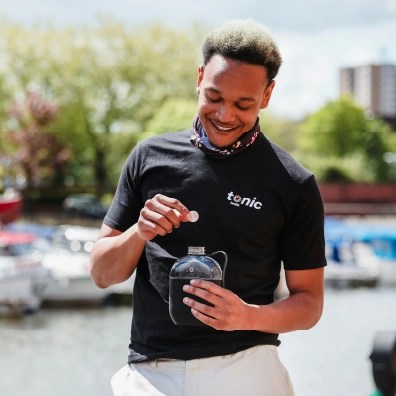 A male smiling while putting a white tablet i his water