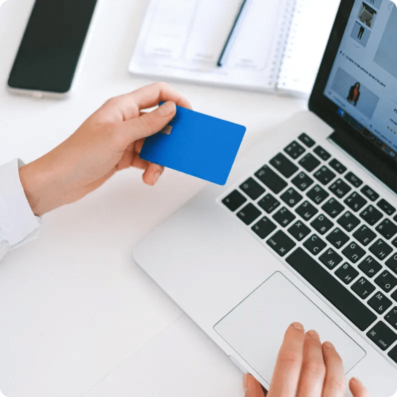 Person on a laptop with payment card in hand.