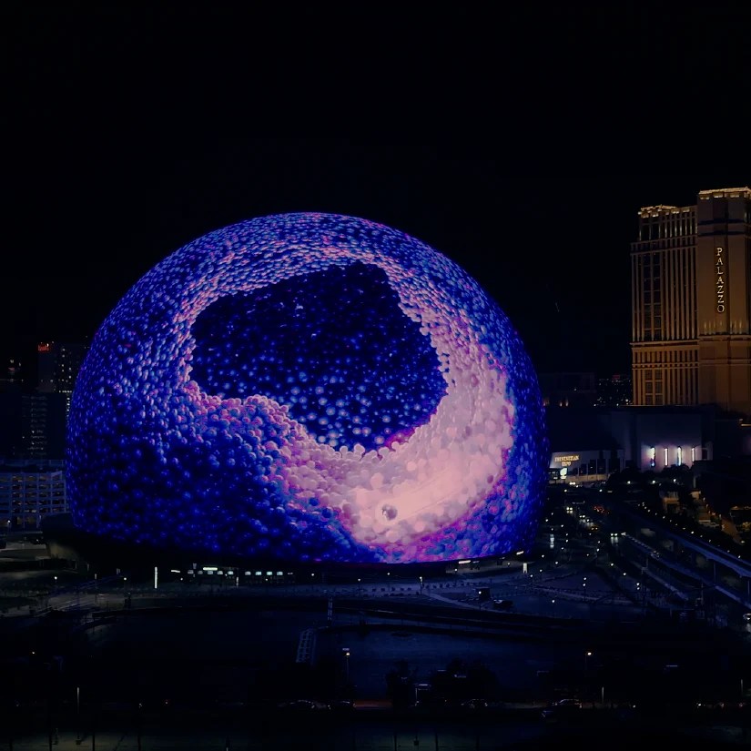 Nighttime view of the Las Vegas Sphere displaying a large illuminated digital animation as part of a DOOH activation.
