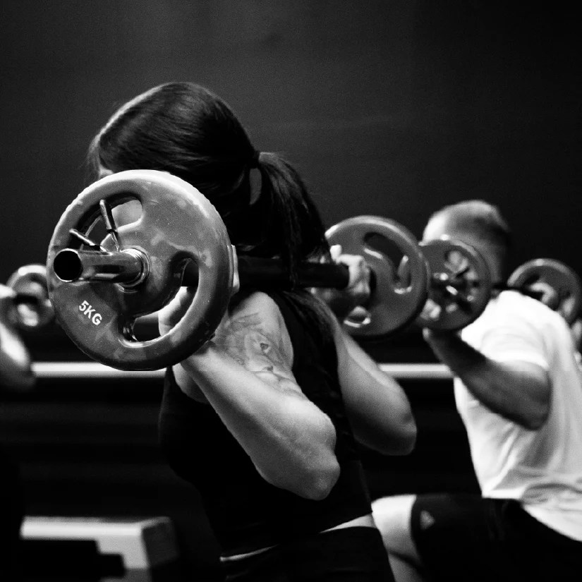 People lifting barbells during a group fitness class at a gym.