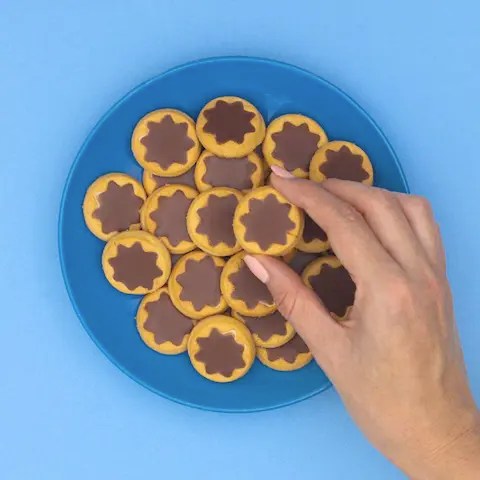 Person reaching for a cookie on a plate