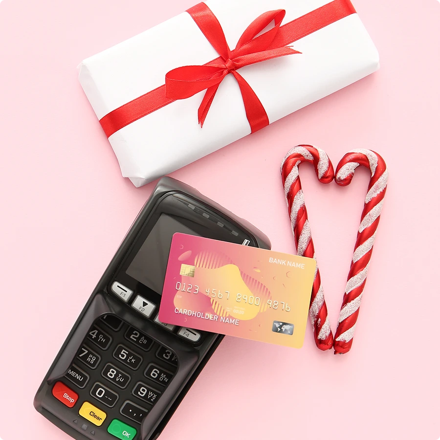 Holiday-themed flat lay with wrapped gift, candy canes, and credit card payment terminal.