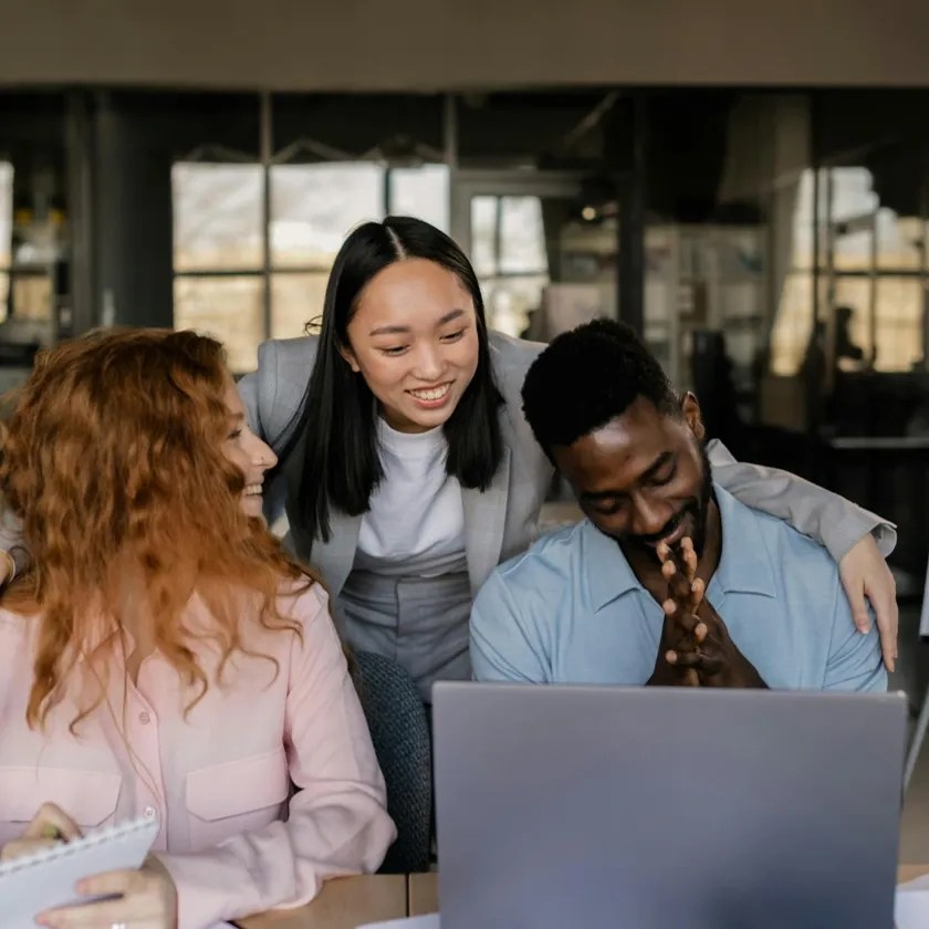 Two female and one male digital advertising buyers in front of a laptop screen